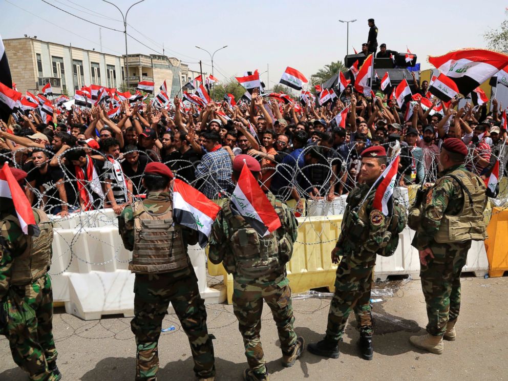 PHOTO: Iraqi security forces guard the heavily fortified Green Zone as followers of Iraqs influential Shiite cleric Muqtada al-Sadr wave national flags as they gather in front of the Green Zone, April 26, 2016, in Baghdad.