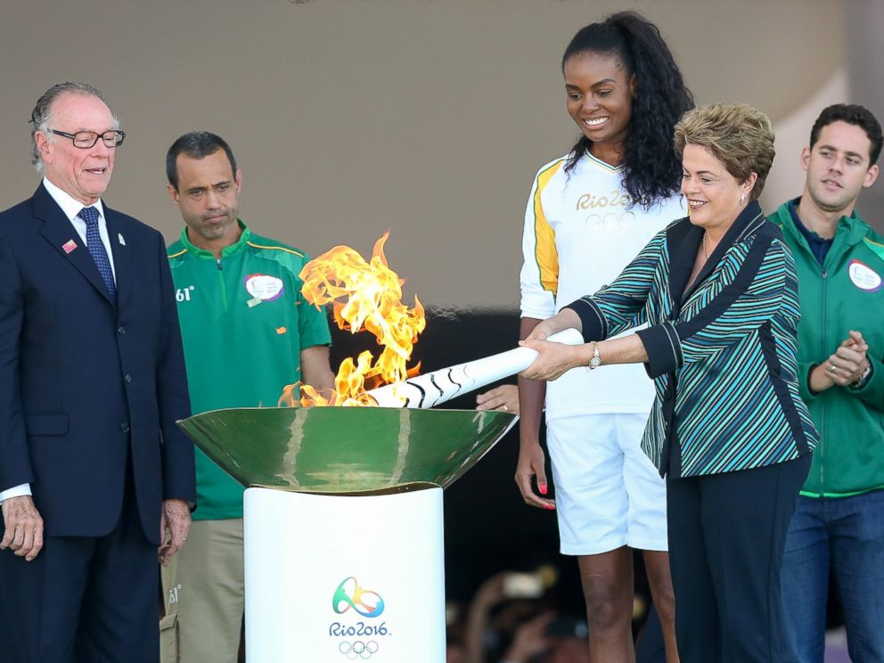 PHOTO: Dilma Rousseff, President of Brazil, lights the Olympic torch with Brazilian Olympic Committee Carlos Nuzman, left, and first torch bearer, volleyball player Fabiana Claudino at the Palacio do Planalto, May 3, 2016 in Brasilia, Brazil.