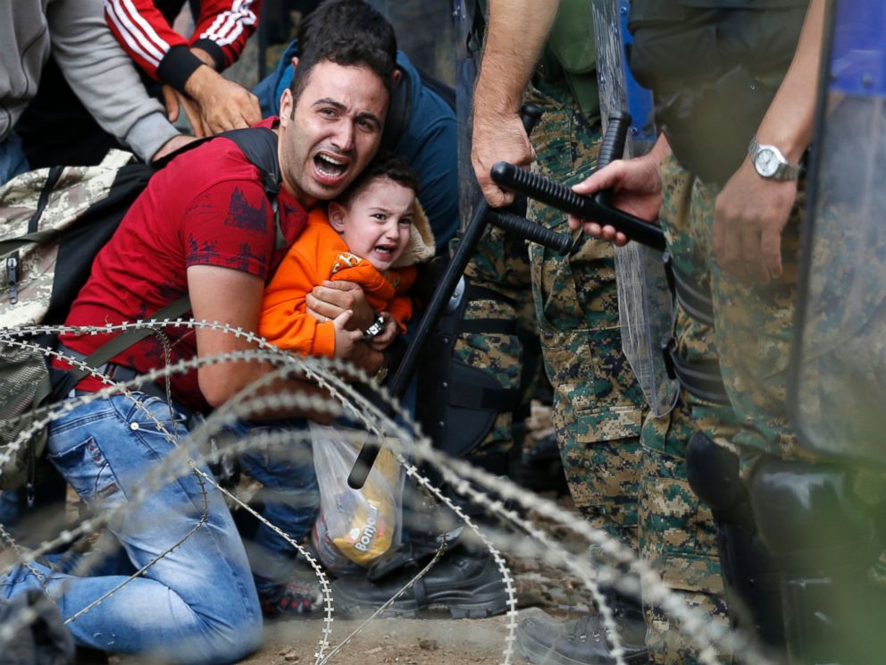 PHOTO:A refugee holding a boy react as they are stuck between Macedonian riot police officers and refugees during a clash near the border train station of Idomeni, northern Greece, Aug. 21, 2015.